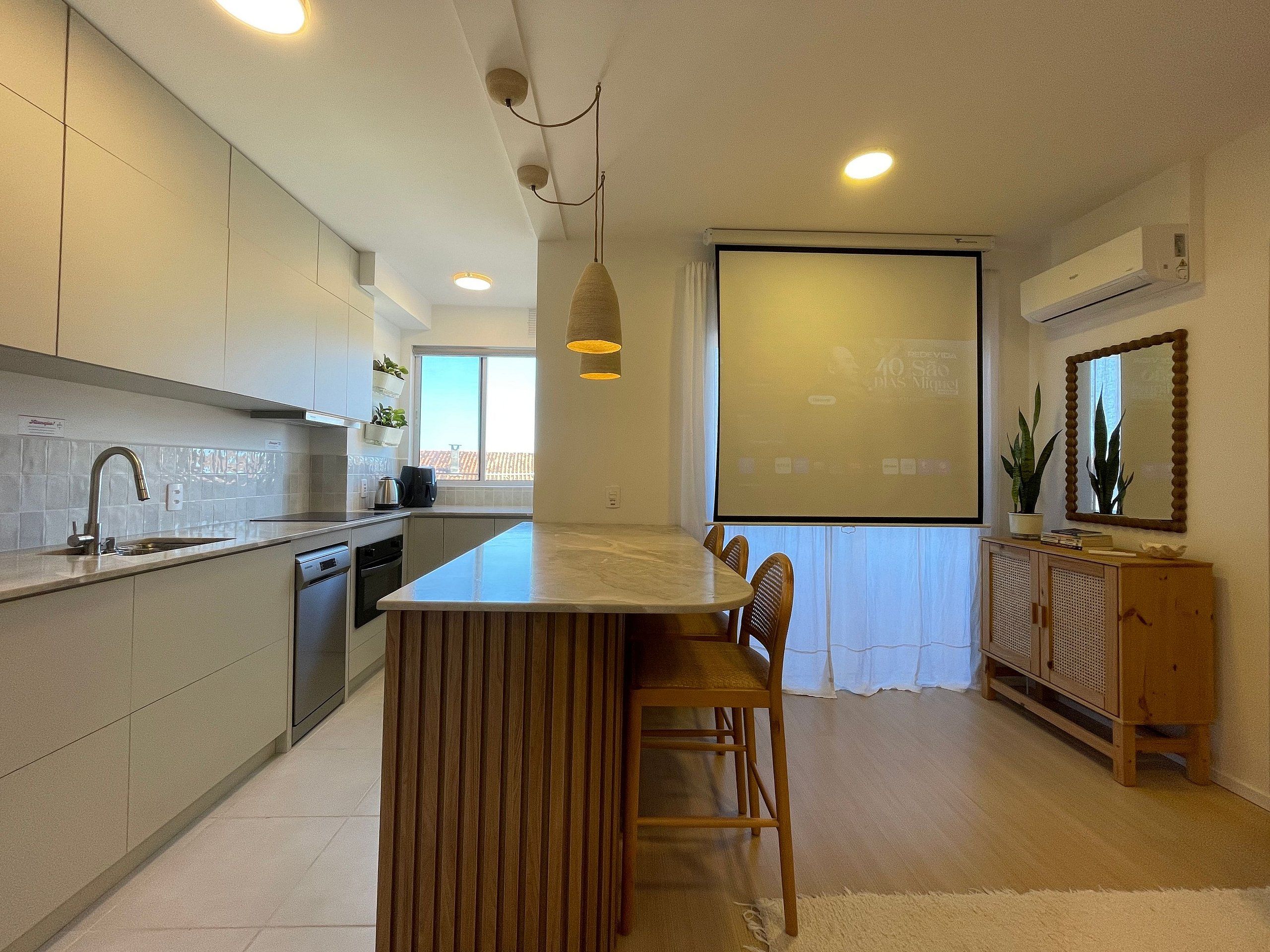A modern kitchen with a central island, built-in appliances, and a dining area with wooden chairs.
