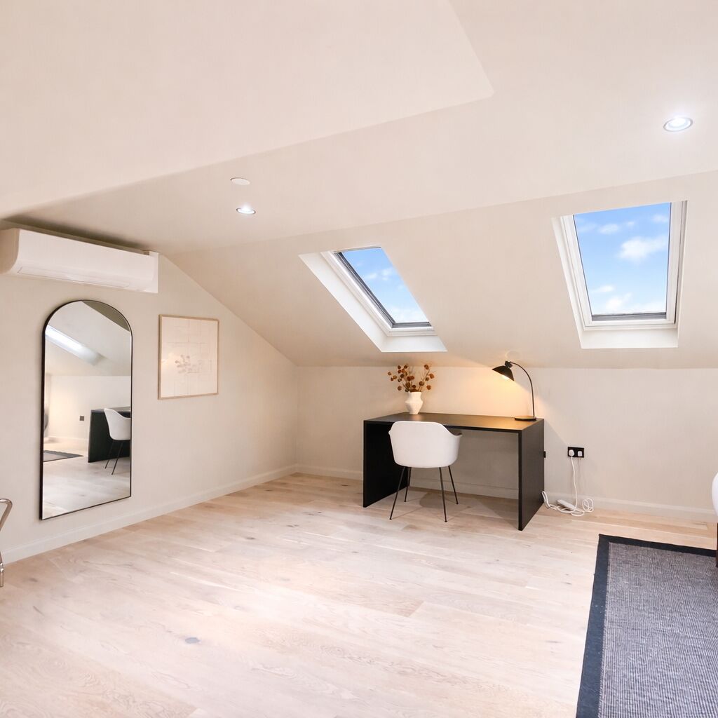 Een moderne loft slaapkamer met dakramen, een bureau en een spiegel.