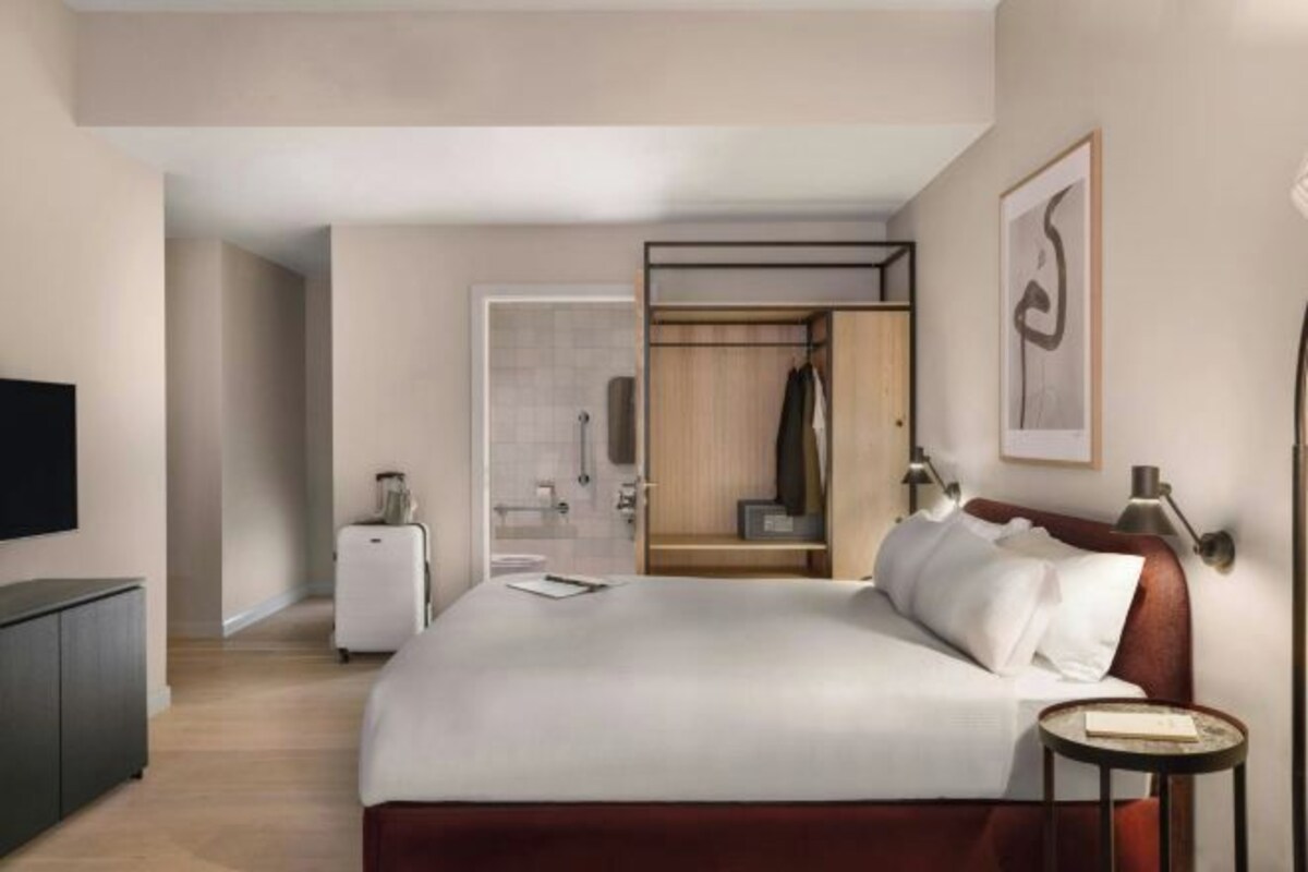 Une chambre d’hôtel avec un lit, une télévision, une armoire et une petite table.