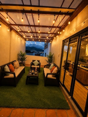 Un patio al aire libre con asientos, una zona de comedor y vistas a la ciudad.