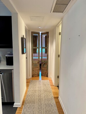 Un couloir doté d’un plancher en bois, d’un tapis à motifs et d’une porte rustique donnant sur l’extérieur.