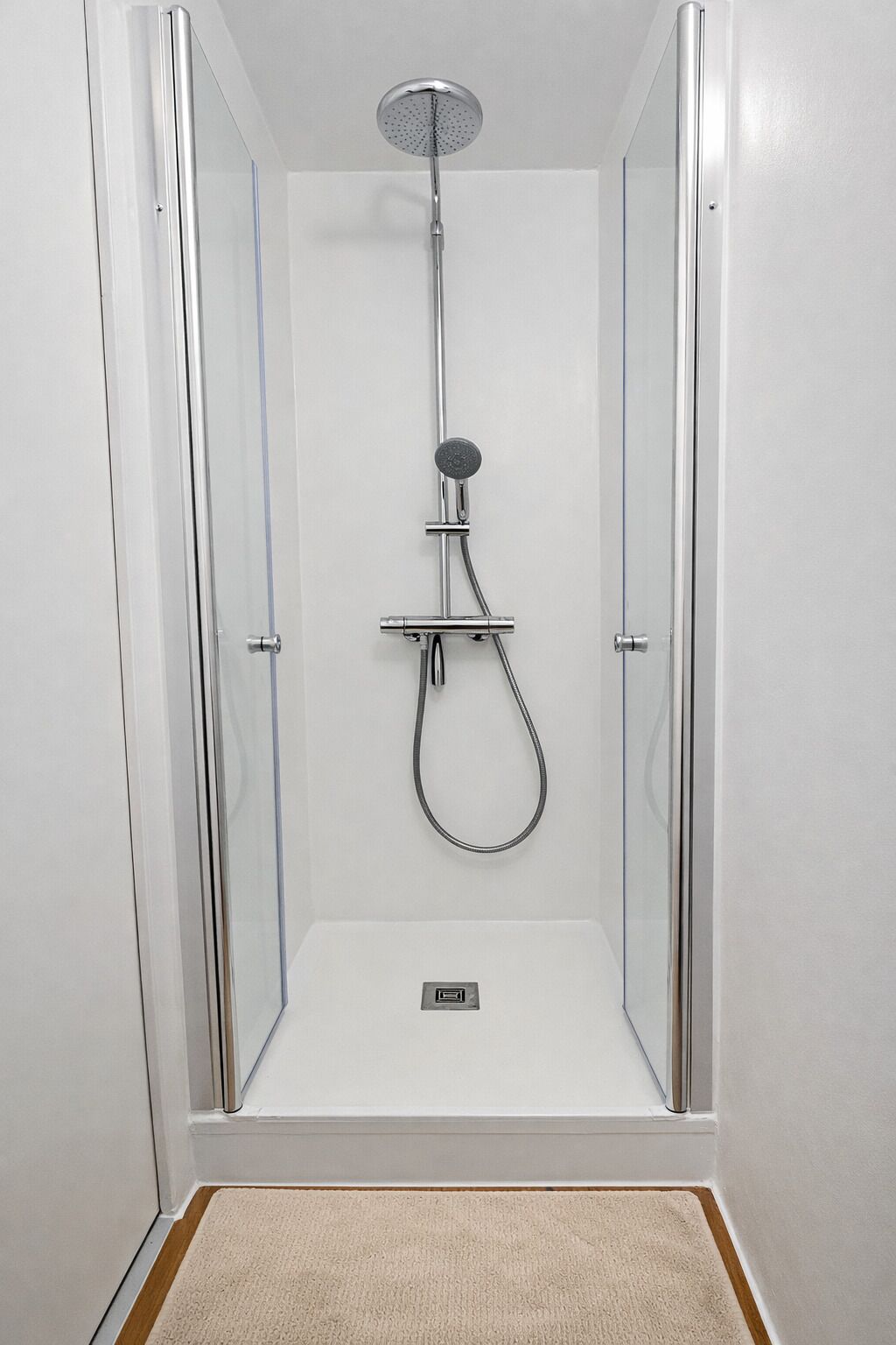A walk-in shower with a handheld showerhead and a handheld shower attachment.