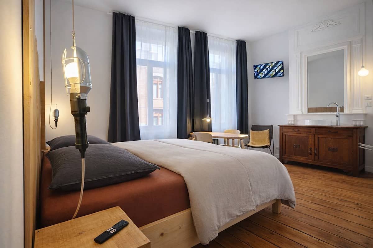 A hotel room with a bed, a desk, a chair, a dresser, and a mirror.