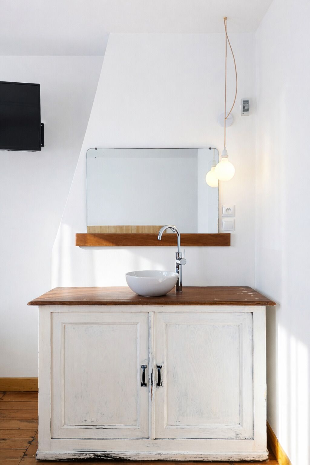 A white cabinet with a wooden countertop and a white bowl sink.