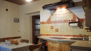 Een keuken met houten kastjes, een betegelde spatwand en een eettafel met stoelen.