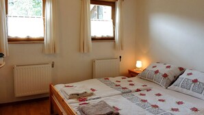 Een slaapkamer met twee bedden, een raam met gordijnen, een radiator en een bedlampje.