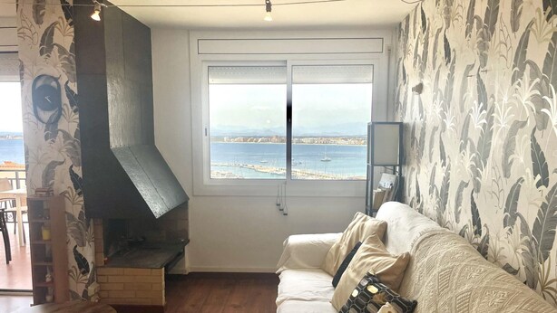 Ein Wohnzimmer mit Kamin, einer Couch und Meerblick.