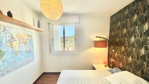 Ein Schlafzimmer mit einem Bett, einer Karte an der Wand, einem Fenster und einer Lampe.