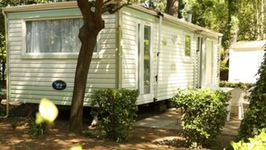 A mobile home with a small porch, surrounded by greenery. - Mobile home with terrace - 6 guests (Montblanc)
