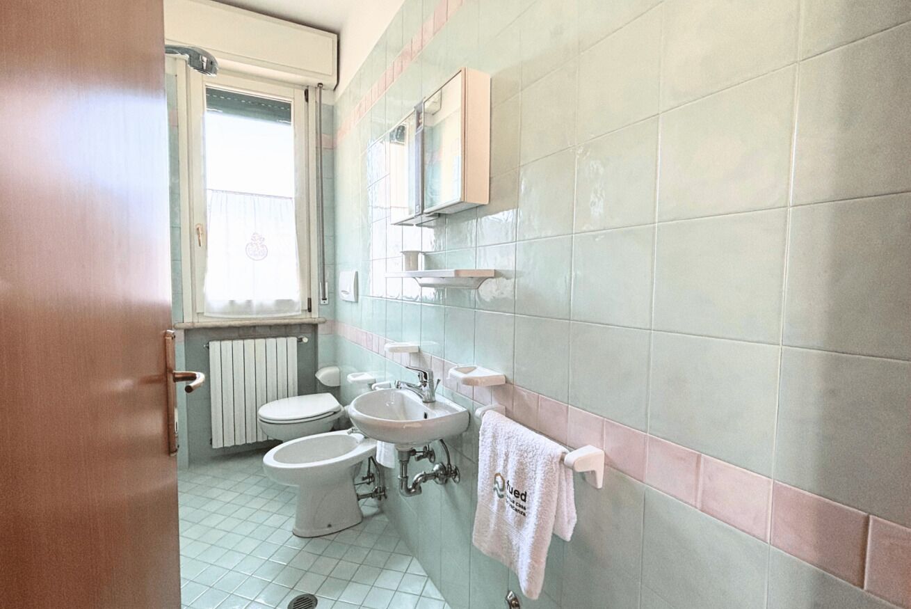 A bathroom with a toilet, bidet, sink, and towel rack.