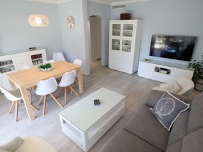 Moderni olohuone, jossa on ruokailutila, televisio ja kaappi.