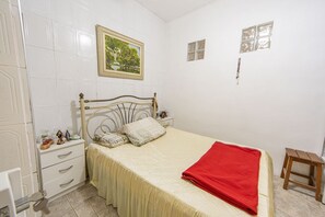Une chambre à coucher avec un lit, une table de chevet, une commode et une fenêtre.