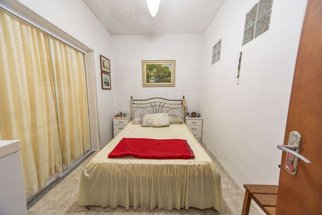 A bedroom with a bed, a nightstand, a dresser, a door, and a window with curtains.