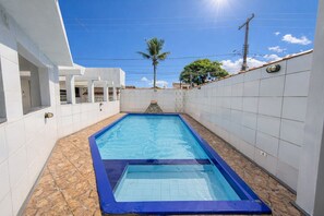 Una piscina rectangular con borde azul, rodeada de paredes y suelo de baldosas blancas.