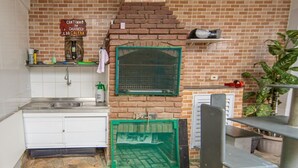 Eine Küche mit Backsteinwand, grünem Fenster, Spüle und Fliesenboden.