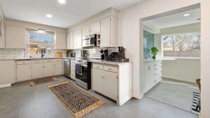 Una cocina moderna con armarios blancos, horno empotrado y un amplio ventanal que proporciona luz natural.