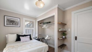 A bedroom with a bed, a window, a closet, and a shelf with plants.
