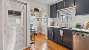 A modern kitchen with dark cabinets, a stainless steel dishwasher, and a window above the sink.