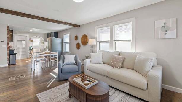 A modern living room with a sofa, coffee table, and a dining area with chairs and a table.