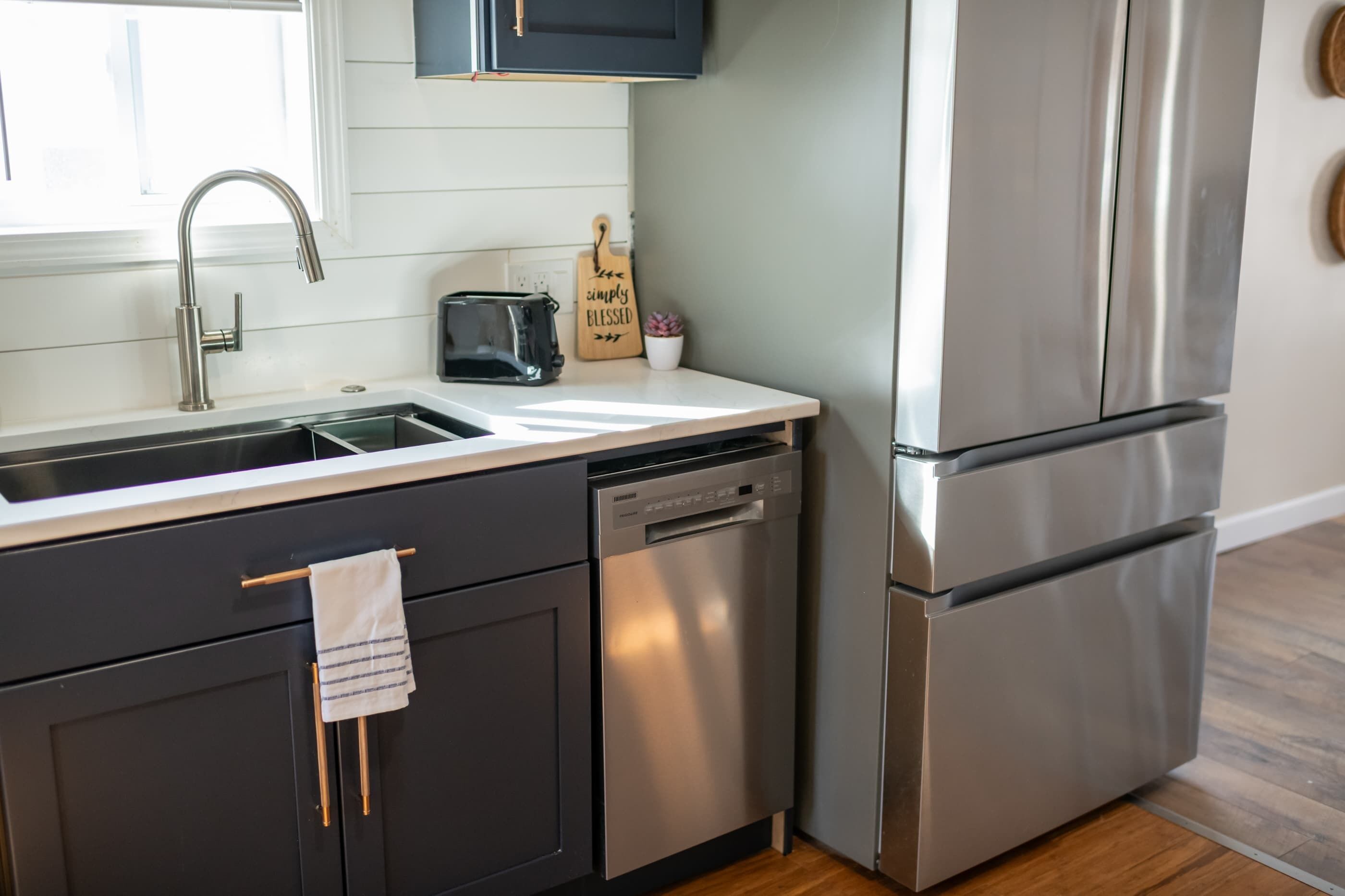 A modern kitchen with a stainless steel refrigerator, a dishwasher, and a toaster.