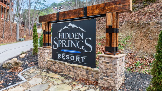 Naamplaatje voor Hidden Springs Resort met een berglogo, een zwembadsymbool en de naam van het resort.