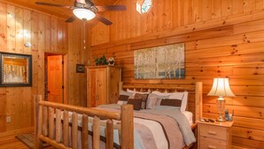 Een houten slaapkamer met een bed, nachtkastje en plafondventilator.
