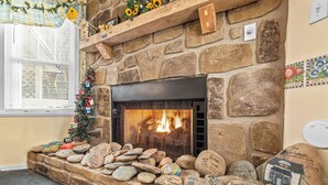 Une cheminée en pierre avec un feu, entourée de roches décorées et portant des inscriptions.