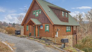 Une cabane en rondins avec un toit végétalisé, une véranda et une enseigne indiquant qu’il s’agit d’un chalet.