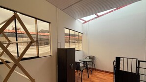 A room with a wooden floor, a desk with a chair, a window, and a door. - Mini-apartment of 02 floors, centrally located and comfortable (Cusco)