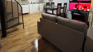 A living room with a sofa, a dining table with chairs, a kitchen area with cabinets and a refrigerator, and a staircase. - Mini-apartment of 02 floors, centrally located and comfortable (Cusco)