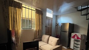 A living room with a sofa, a glass table, a TV, and a refrigerator. - Mini-apartment of 02 floors, centrally located and comfortable (Cusco)