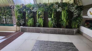 A hotel lobby with a large indoor garden wall, a tiled floor, and a metal railing. - New VC Hotel Bangkok (Bangkok)