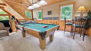 A pool table in a wooden room with a high ceiling and large windows. - Caught Up In The Mountains (PIGEON FORGE)
