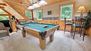 A pool table in a wooden room with a high ceiling and large windows. - Caught Up In The Mountains (PIGEON FORGE)