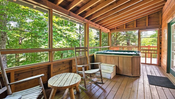 A wooden deck with a hot tub, wooden chairs, and a table. - Caught Up In The Mountains (PIGEON FORGE)
