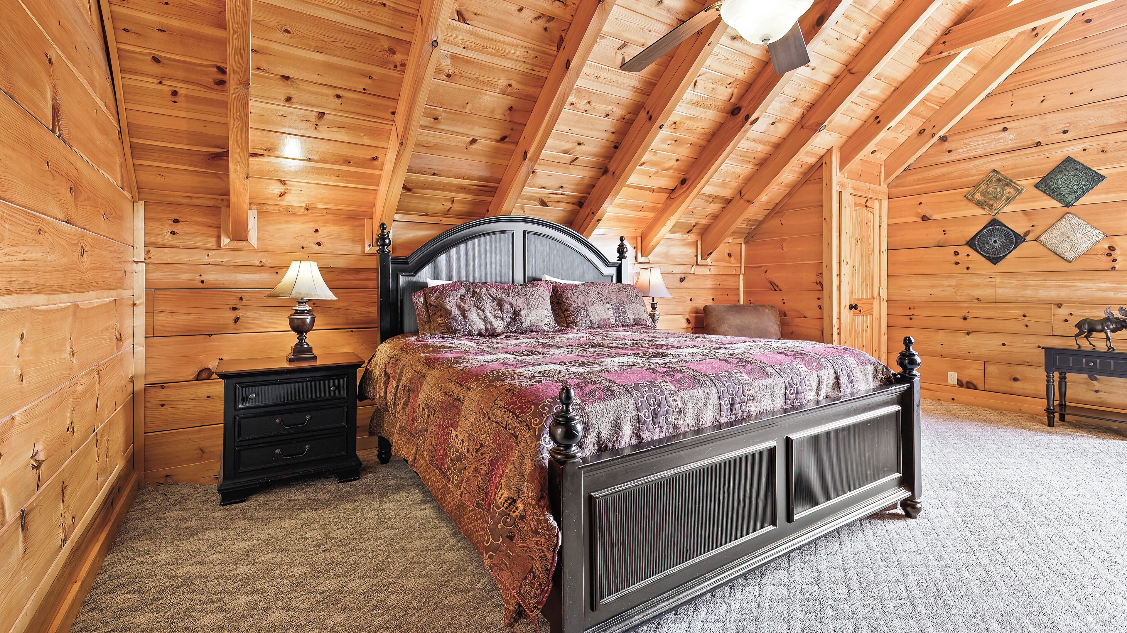 A wooden cabin bedroom with a bed, nightstands, and a decorative wall.
