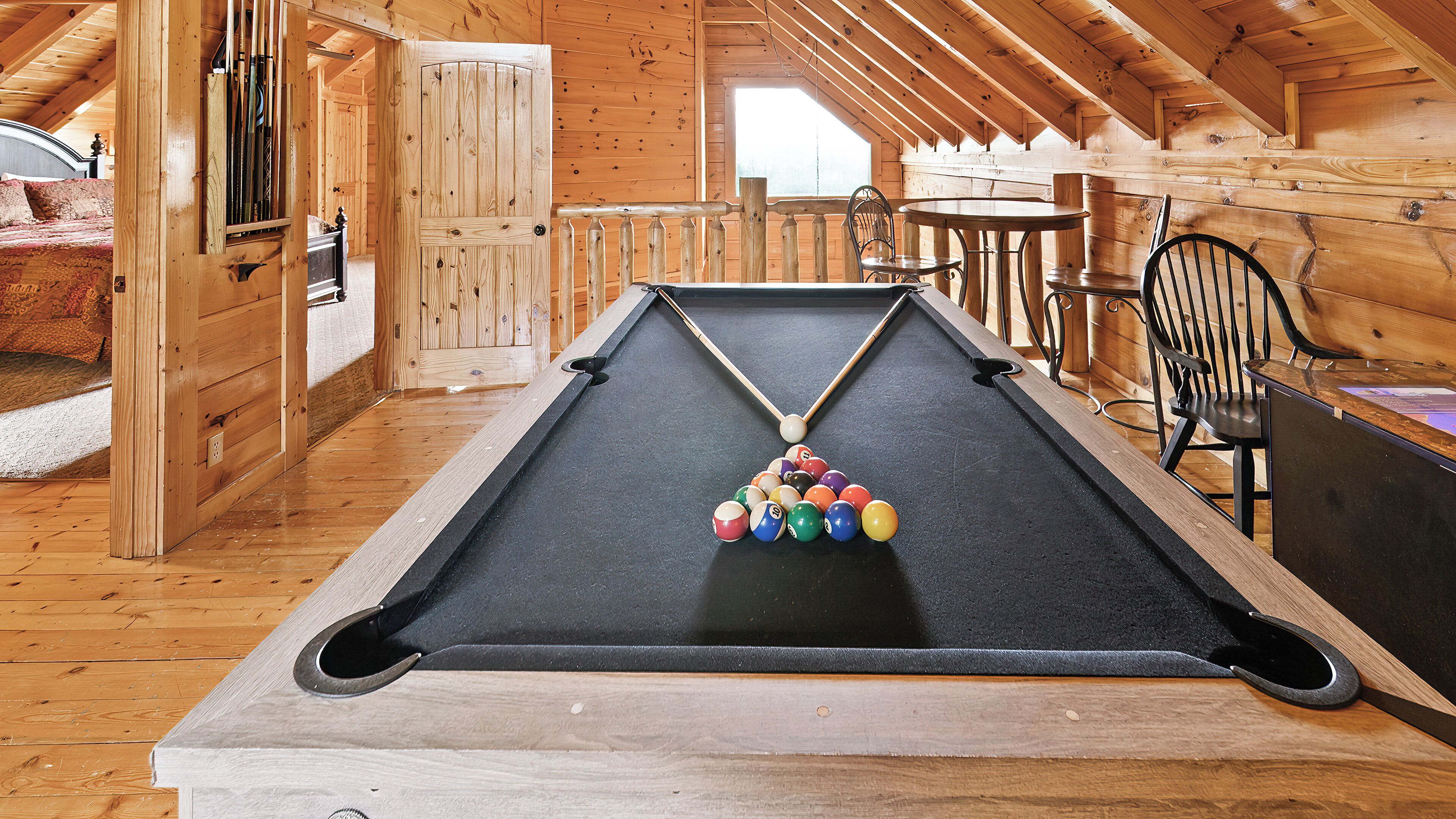 Une table de billard dans une pièce en bois avec un plafond en pente, une table à manger et des chaises.