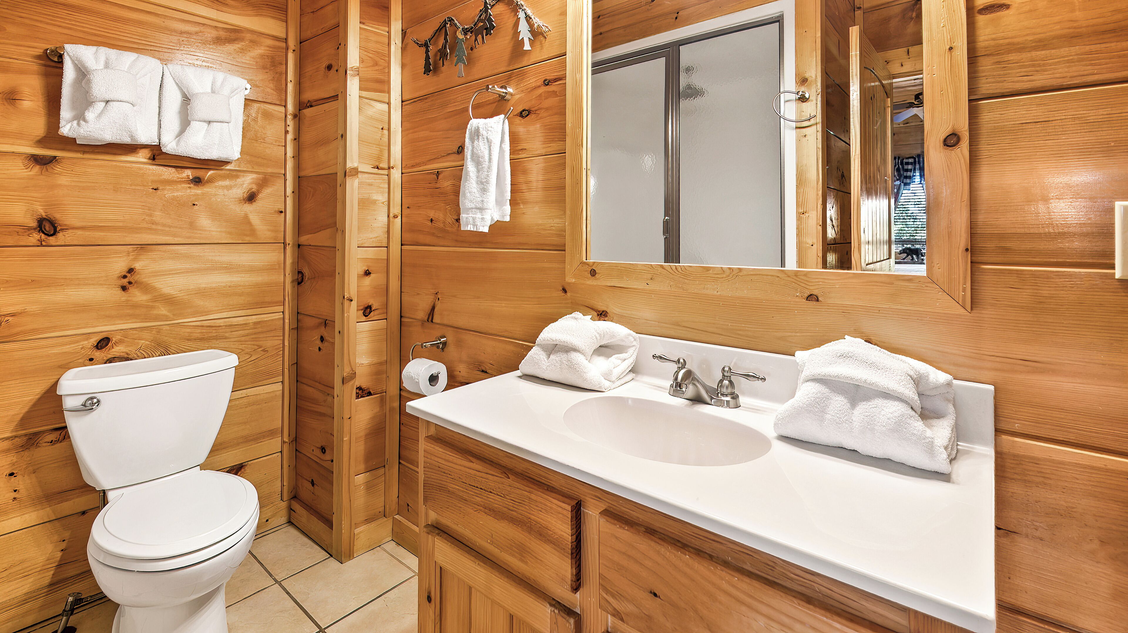 Un baño de madera con inodoro, lavamanos y espejo.