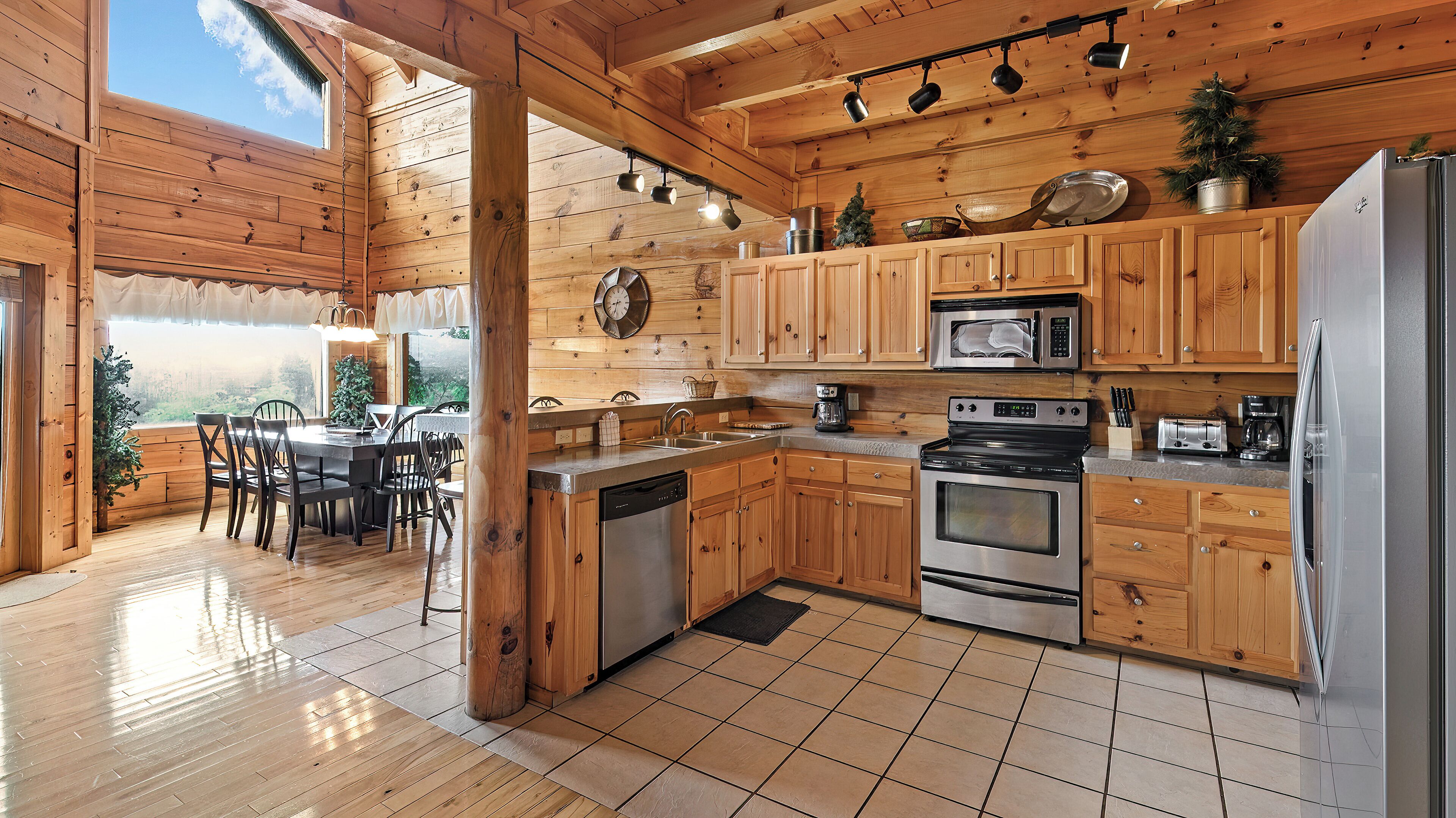 Cocina de cabaña de madera con comedor, armarios de madera, lavavajillas, estufa y refrigerador.