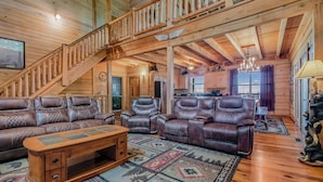A spacious living room with leather sofas, a wooden coffee table, and a staircase leading to an upper level. - Riding The Feathers Of Heaven (GATLINBURG)