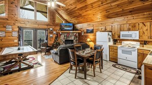 Interior acolhedor de uma cabana, com área de jantar, cozinha e lareira.