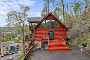 Eine rote Blockhütte mit Balkon, Treppe und Blick auf die Umgebung.