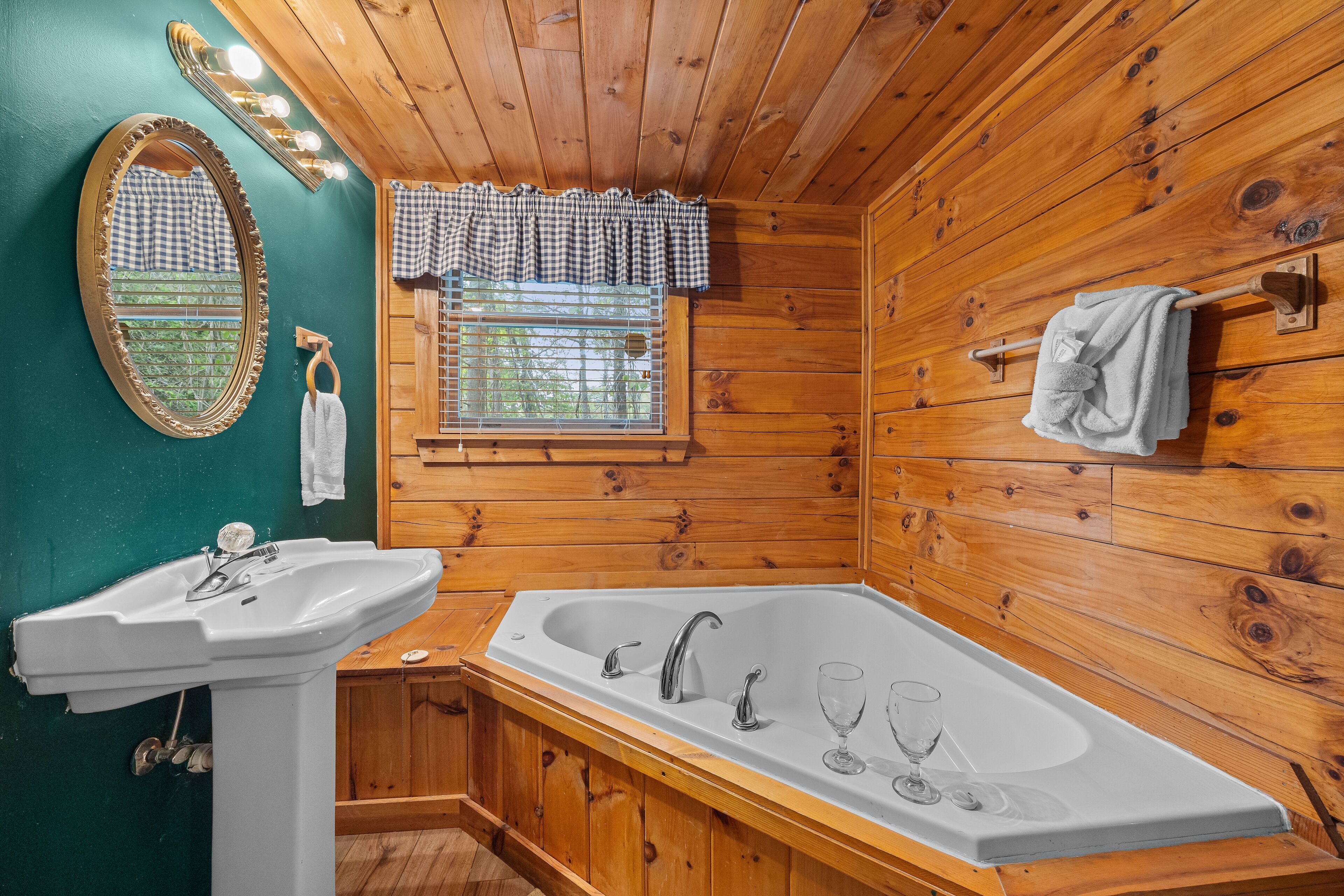 Un baño con lavamanos, bañera y ventana con cortina a cuadros.