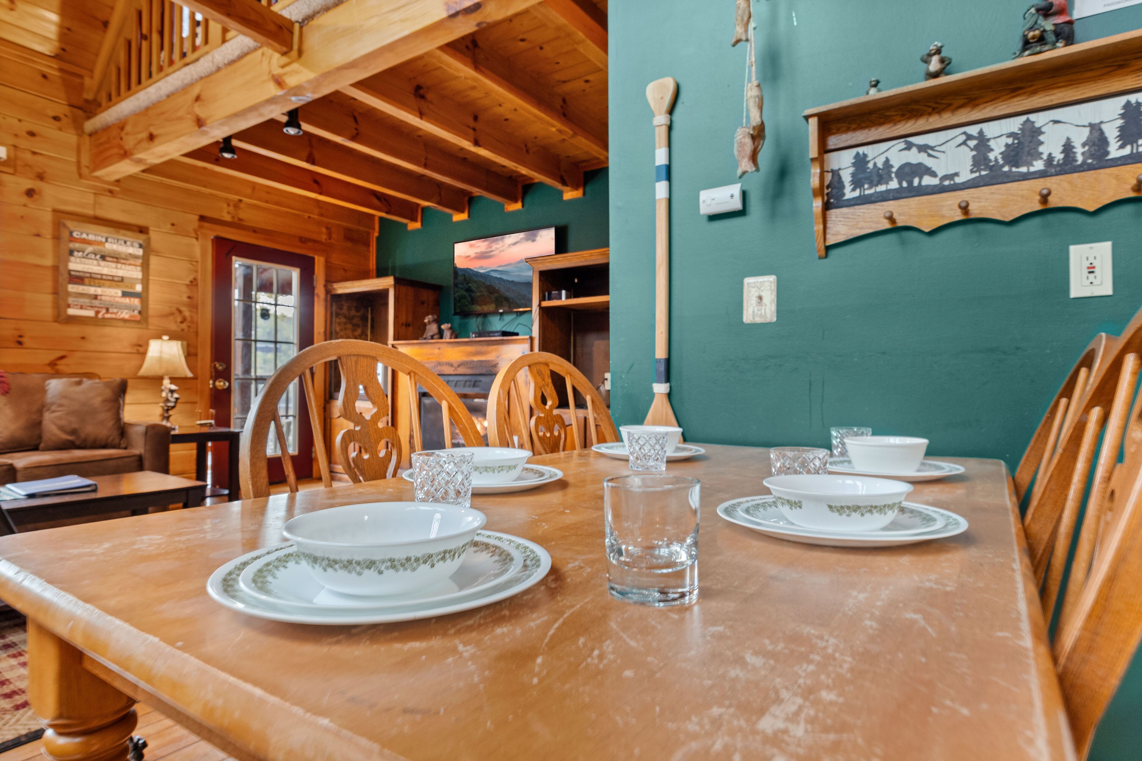 A wooden dining table set with plates, bowls, and a glass.
