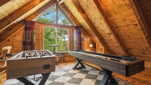 Una stanza accogliente con pareti in legno e soffitto a falde, con tavolino da calcio e tavolo da gioco.