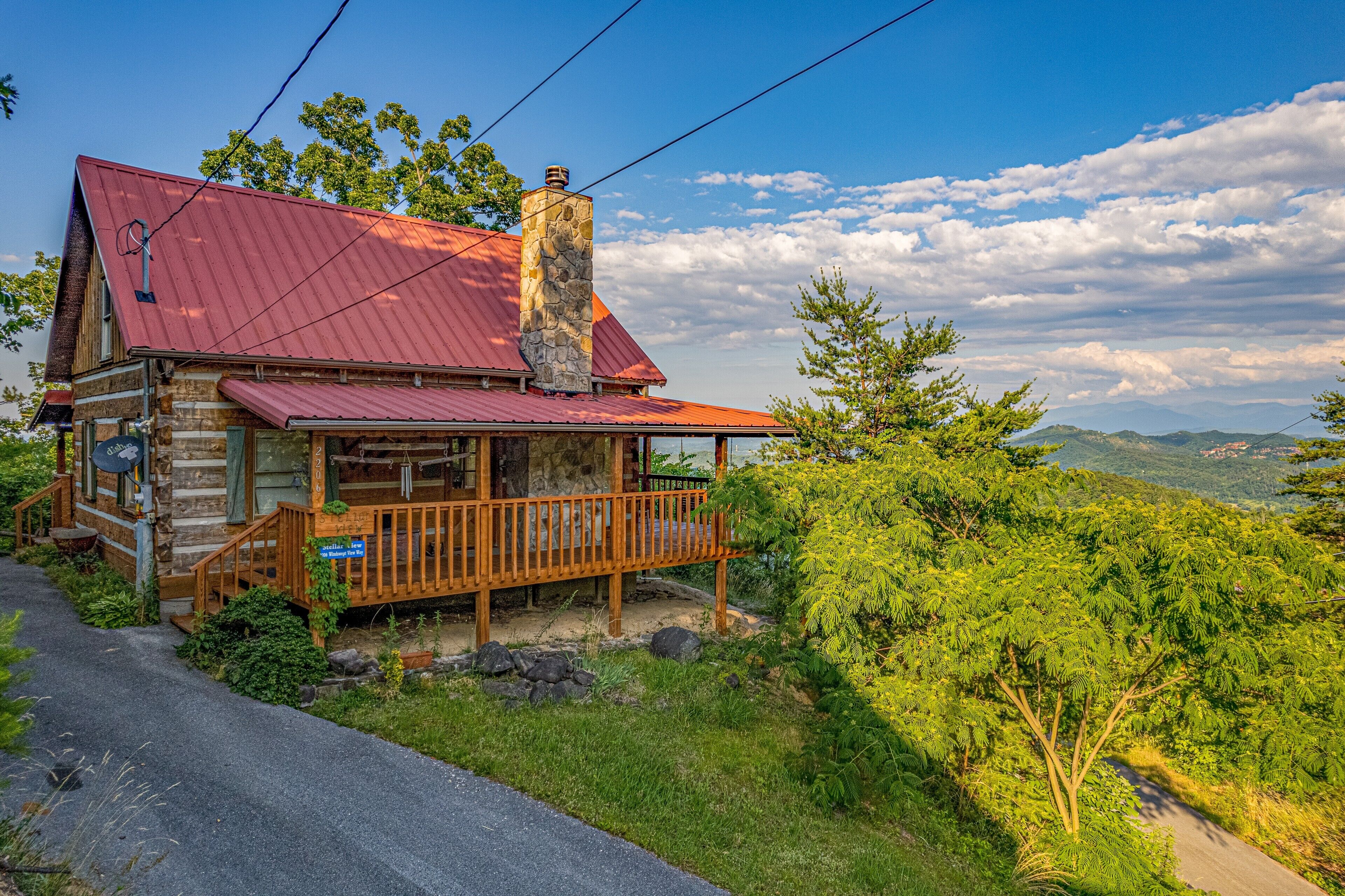 Un rustico chalet con camino in pietra, portico in legno e uno splendido sfondo montano.