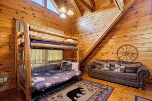 A cozy cabin interior with a bunk bed, a leather sofa, and a rustic wooden ceiling. - Luxury Resort*Close to Dollywood*Sleeps 10 (Pigeon Forge)