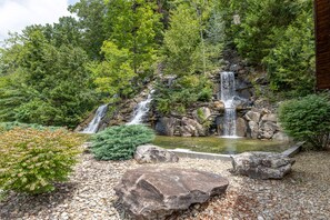 Une cascade entourée d’une végétation luxuriante et un petit étang.