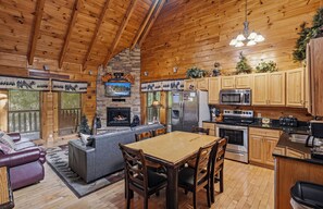 L’intérieur d’une cabane comprend une cheminée, une table à manger en bois, un coin cuisine et un espace salon confortable.
