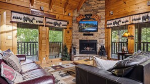 A wooden cabin interior with a fireplace, leather sofas, and a television mounted above it. - Resort Location*15 minutes to Dollywood*Sleeps 10 (Pigeon Forge)